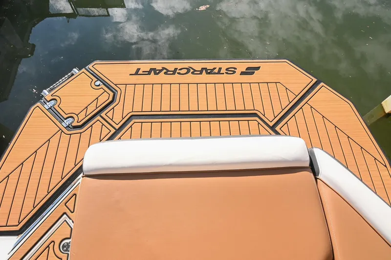 Slide: The Image of 2023 Starcraft SVX 230 IO boat deck with cushioned seating, docked on water. - 7