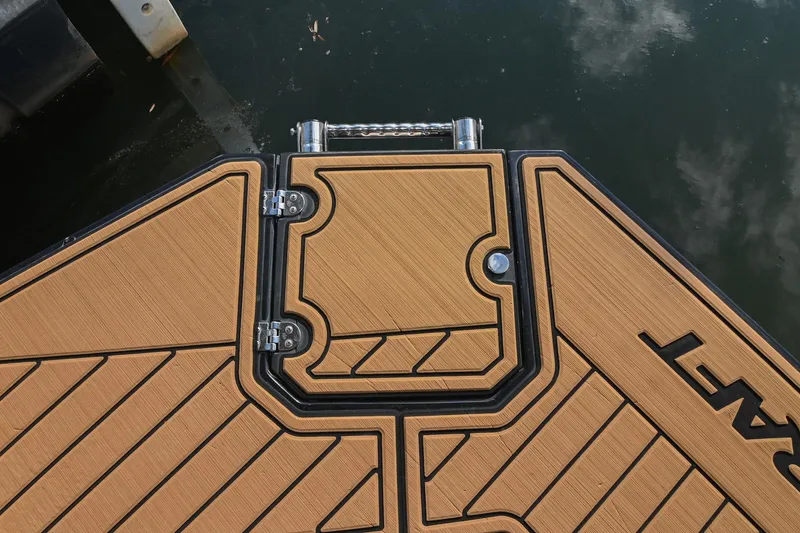 Slide: The Image of 2023 Starcraft SVX 230 IO boat deck with teak-style finish and water reflection. - 8