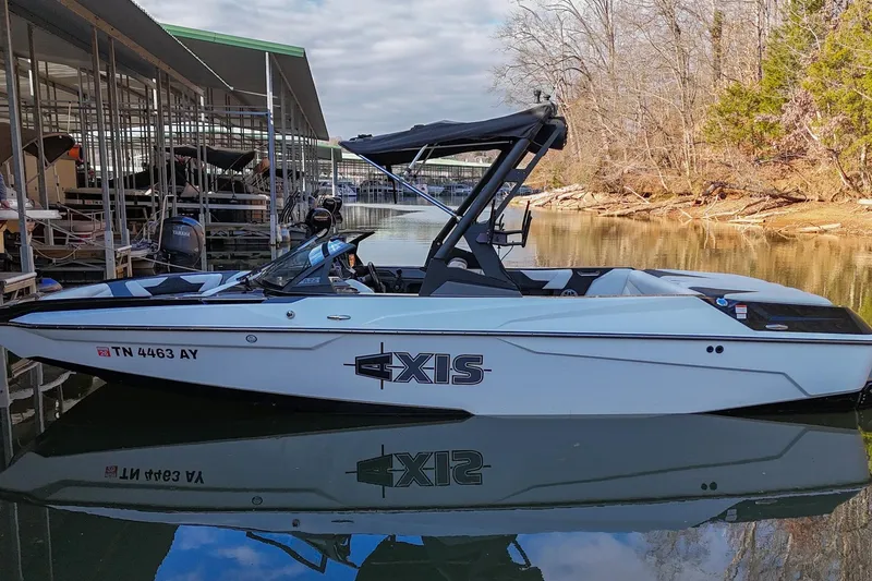 The Image of 2022 Axis A22 boat docked on calm water, surrounded by trees and marina. - 0