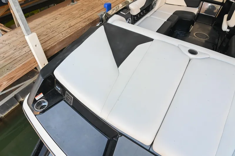 Slide: The Image of 2022 Axis A22 boat interior with white and black seating near a wooden dock. - 10