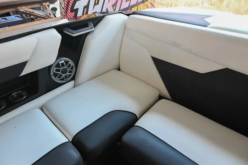 Slide: The Image of 2022 Axis A22 boat interior with white and black seating, speaker, and cup holders. - 17