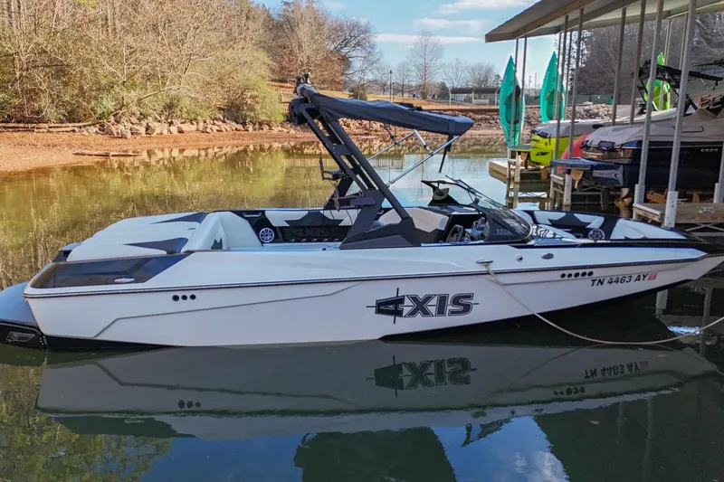 Slide: The Image of 2022 Axis A22 boat docked on a calm lake with trees in the background. - 3