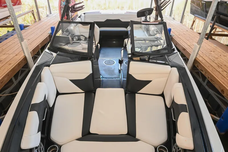 Slide: The Image of 2022 Axis A22 boat interior with white and black seating, docked in a covered area. - 7