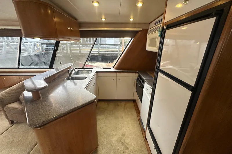 Slide: The Image of 1999 Bayliner 4788 Pilot House Motoryacht interior kitchen with modern amenities and large windows. - 13