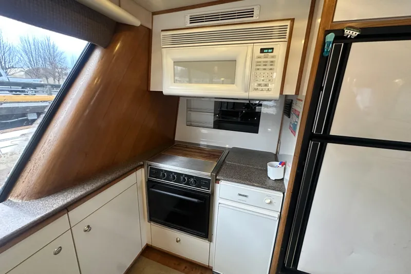 Slide: The Image of 1999 Bayliner 4788 Pilot House Motoryacht kitchen with stove, microwave, and cabinets. - 14