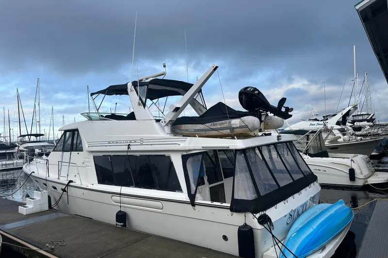 Slide: The Image of 1999 Bayliner 4788 Pilot House Motoryacht docked at marina under cloudy sky. - 2