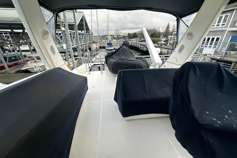 Slide: The Image of 1999 Bayliner 4788 Pilot House Motoryacht deck view with covered seating and marina backdrop. - 26