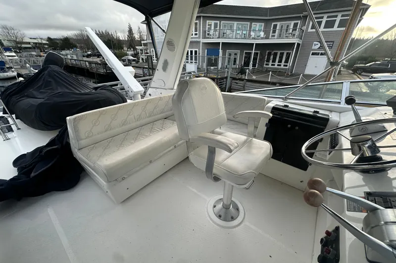 Slide: The Image of 1999 Bayliner 4788 Pilot House Motoryacht helm with seating and steering wheel, docked at marina. - 29