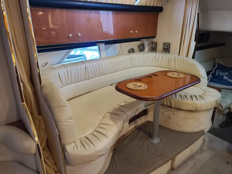 Slide: The Image of 1999 Sea Ray 340 Sundancer interior with beige sofa and wooden table. - 10