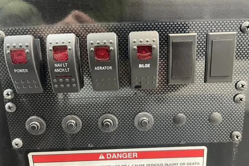 Slide: The Image of Control panel of 2025 SeaArk Shadow 187T boat with labeled switches and warning sign. - 13