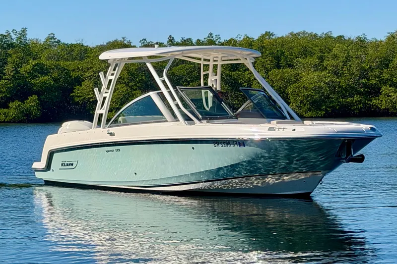 Slide: The Image of 2018 Boston Whaler 230 Vantage boat on calm water, surrounded by lush greenery. - 0