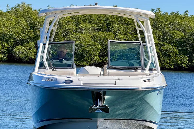 Slide: The Image of 2018 Boston Whaler 230 Vantage boat on calm water, surrounded by greenery. - 1