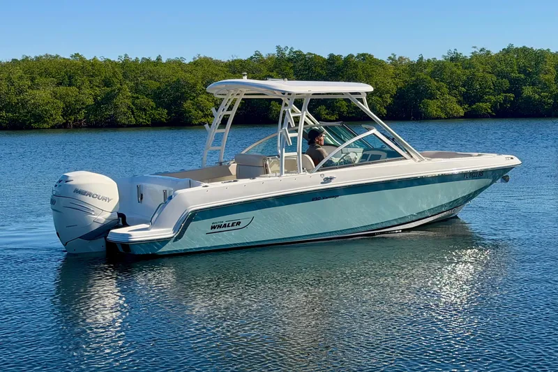 Slide: The Image of 2018 Boston Whaler 230 Vantage boat on calm water with lush green background. - 3