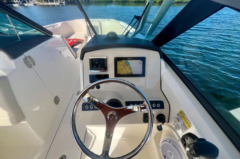 Slide: The Image of 2018 Boston Whaler 230 Vantage helm with steering wheel and navigation display on water. - 5