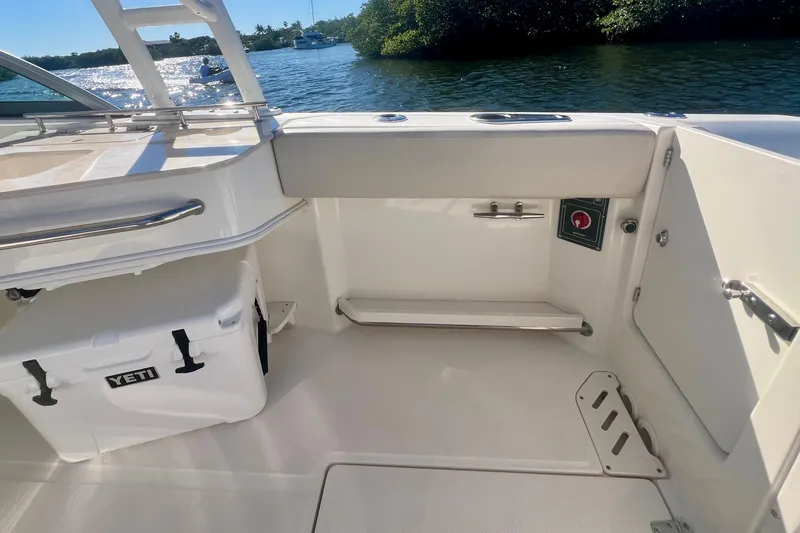 Slide: The Image of 2018 Boston Whaler 230 Vantage interior with Yeti cooler, docked by scenic waterway. - 8