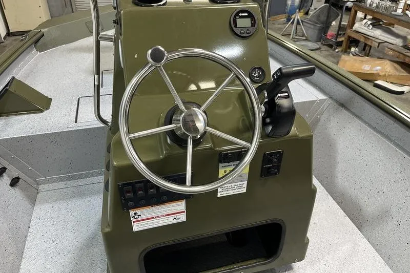 Slide: The Image of 2025 SeaArk Shadow 187J boat console with steering wheel and controls in a workshop. - 7