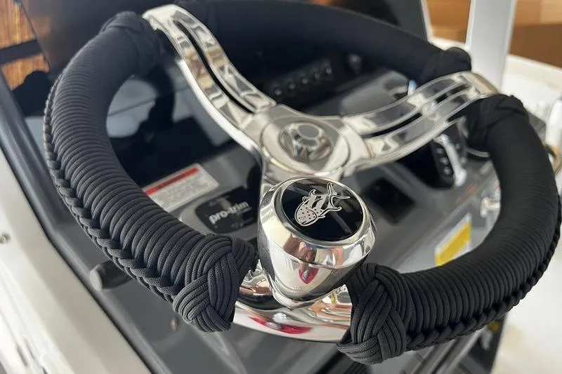Slide: The Image of Steering wheel of 2025 Crevalle 26 HCO boat, featuring sleek design and black grip. - 10