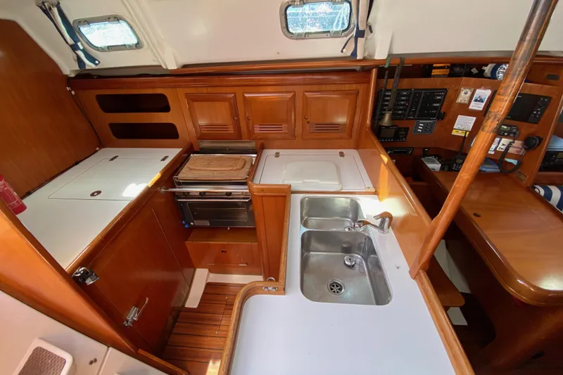 Slide: The Image of 2001 Beneteau Oceanis 361 yacht interior kitchen with wooden cabinetry and dual sink. - 47