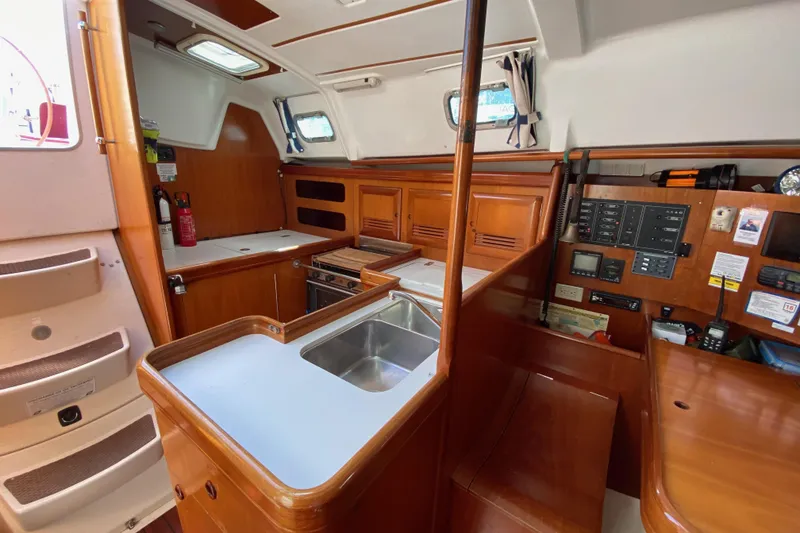 Slide: The Image of Interior of 2001 Beneteau Oceanis 361 sailboat, featuring a compact kitchen and navigation panel. - 68