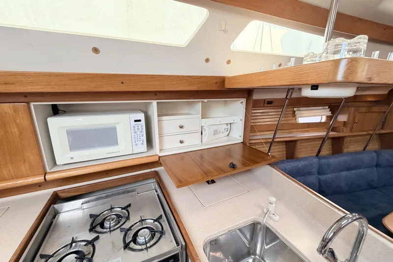Slide: The Image of 2001 Catalina 380 yacht kitchen with stove, microwave, and wooden cabinetry. - 24
