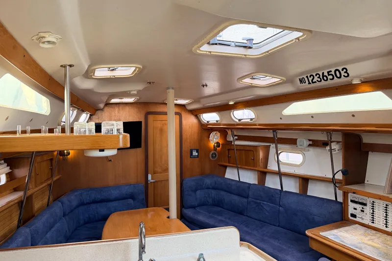 Slide: The Image of Interior of a 2001 Catalina 380 sailboat with blue seating and wooden accents. - 26