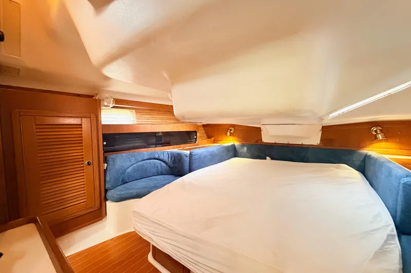 Slide: The Image of Cozy cabin interior of 2001 Catalina 380 sailboat with blue seating and wooden accents. - 30