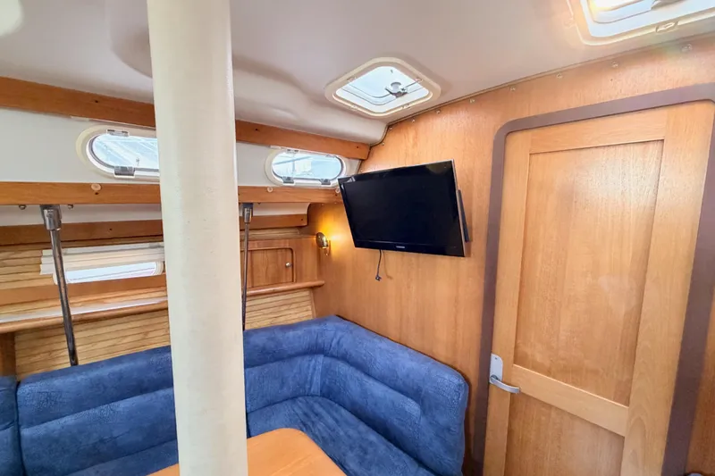 Slide: The Image of Interior of 2001 Catalina 380 sailboat with blue seating and mounted TV. - 37