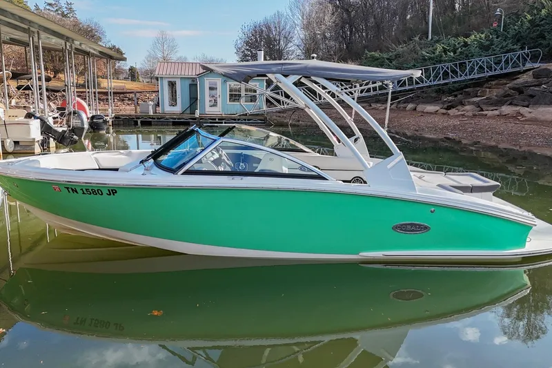 Slide: The Image of 2023 Cobalt CS22 boat docked on calm water, featuring a sleek green exterior. - 4