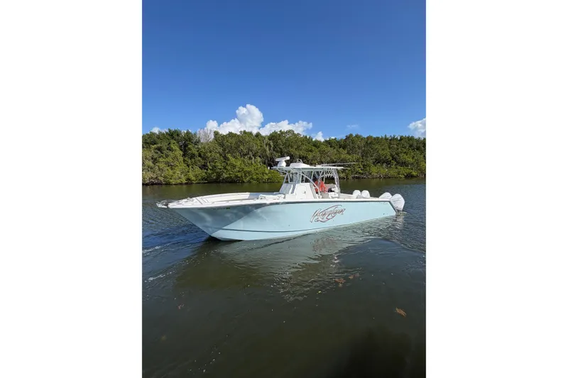 The Image of 2022 SeaHunter 38 CTS boat cruising on a calm river with lush greenery. - 1