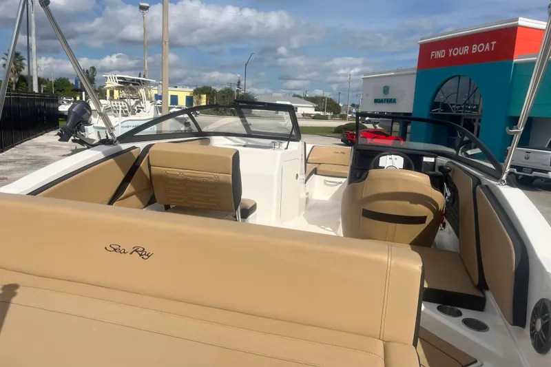 Slide: The Image of 2024 Sea Ray SPX 210 Outboard boat with tan seating, docked under a blue sky. - 8