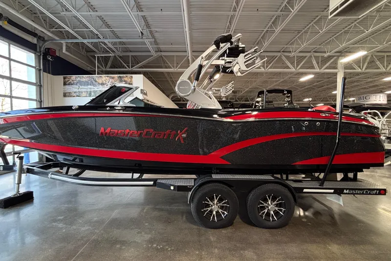 The Image of 2017 MasterCraft X46 boat in showroom, black and red design on trailer. - 1