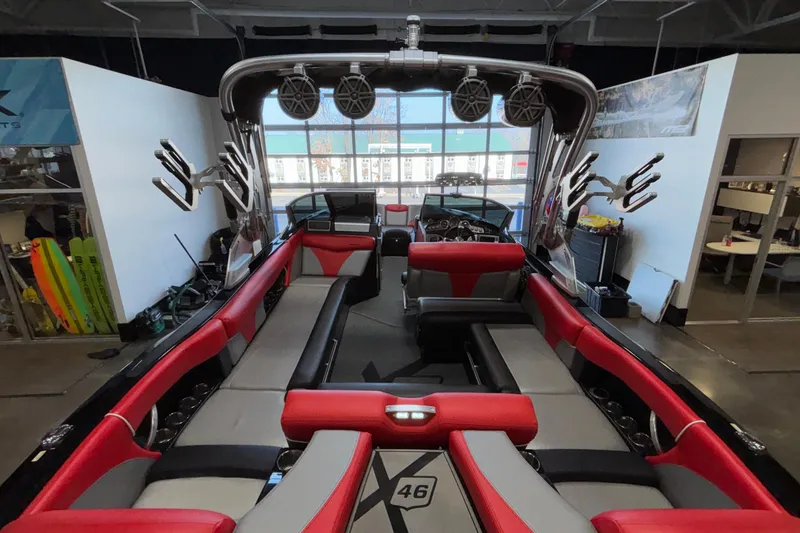 Slide: The Image of 2017 MasterCraft X46 boat interior with red and gray seating, tower speakers, and wakeboard racks. - 10