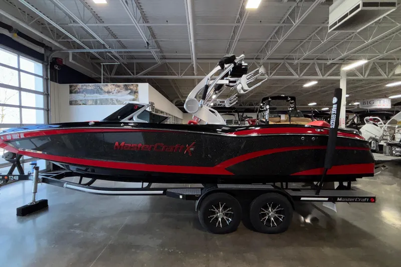Slide: The Image of 2017 MasterCraft X46 boat in showroom, black and red design, on trailer. - 49