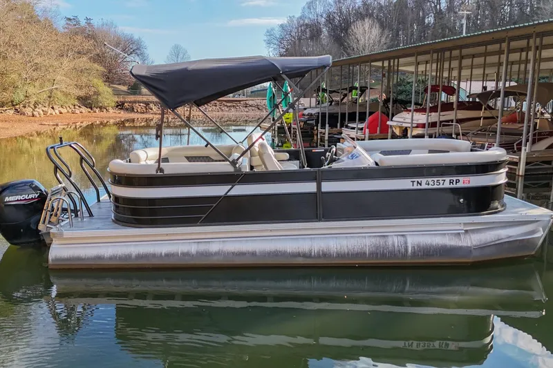 The Image of 2021 Crest Classic DLX 220 L pontoon boat docked on a calm lake. - 0