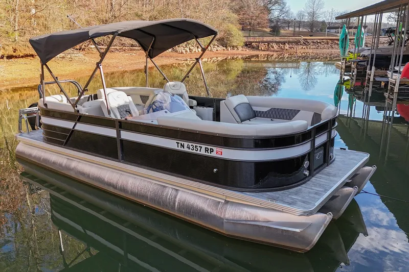 Slide: The Image of 2021 Crest Classic DLX 220 L pontoon boat docked on a calm lake. - 1