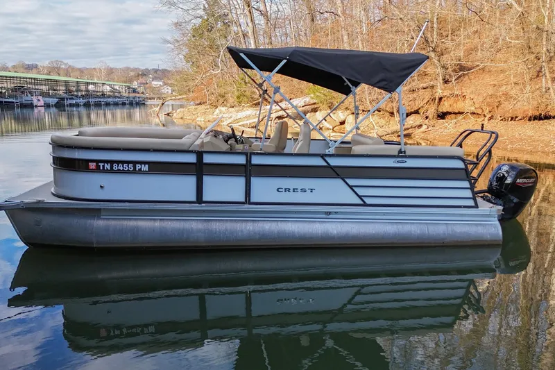 The Image of 2022 Crest CLASSIC 220 SLC pontoon boat on calm lake with trees in background. - 0
