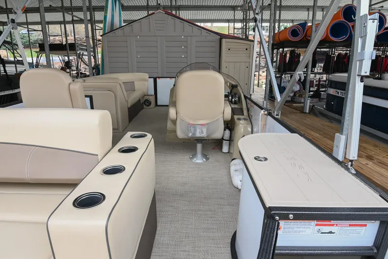 Slide: The Image of 2022 Crest Classic DLX 220 pontoon boat interior with beige seating and storage compartments. - 12