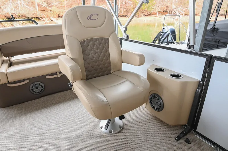 Slide: The Image of Captain's chair on 2022 Crest Classic DLX 220 pontoon boat, featuring beige upholstery and cup holders. - 18