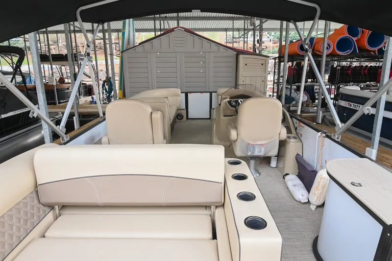 Slide: The Image of 2022 Crest Classic DLX 220 pontoon boat interior with beige seating and storage compartments. - 5