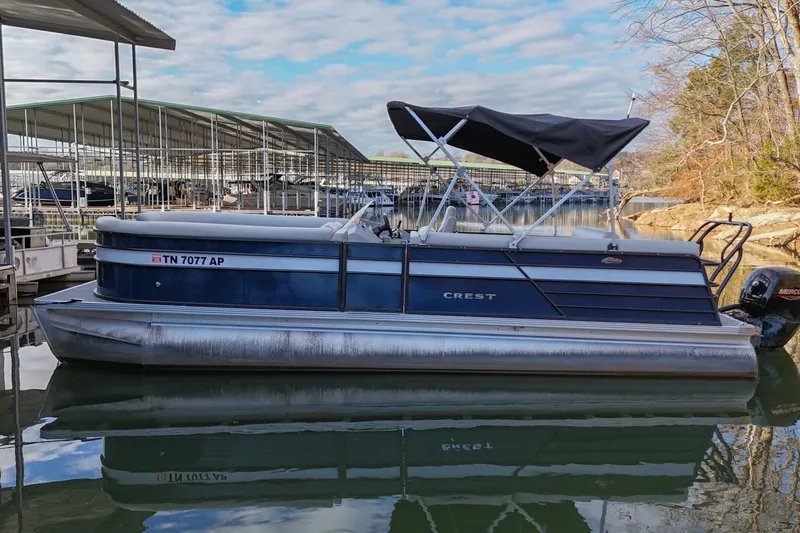 The Image of 2022 Crest Classic DLX 220 pontoon boat docked at marina, under blue sky. - 0