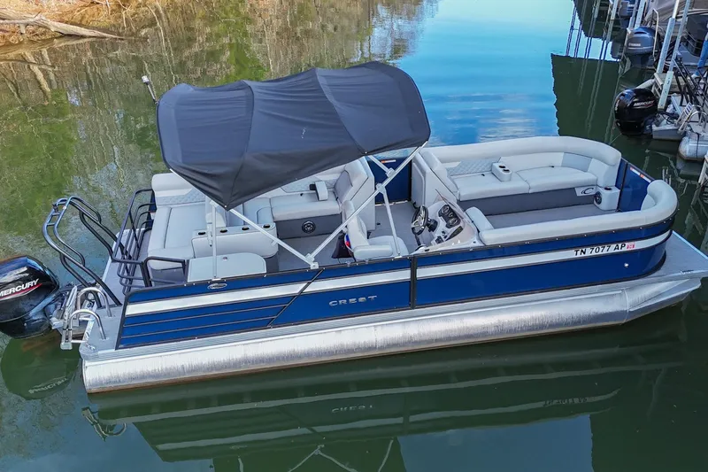 Slide: The Image of 2022 Crest Classic DLX 220 pontoon boat with canopy on calm water. - 3