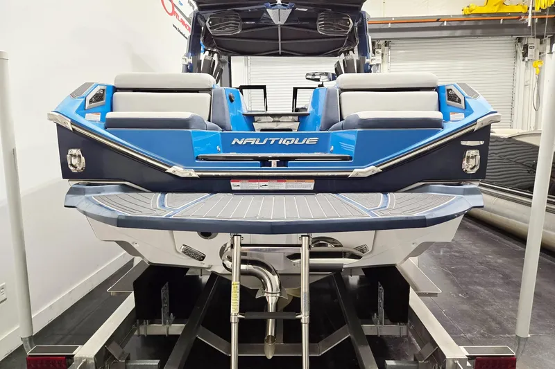 Slide: The Image of 2022 Nautique Super Air Nautique G25 Paragon boat, blue and white, rear view on trailer. - 2