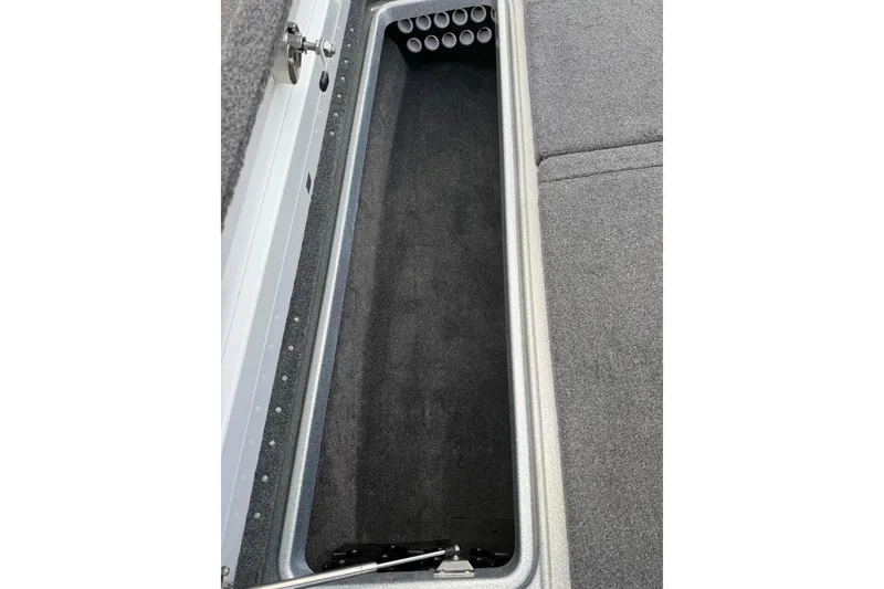 Slide: The Image of 2018 Phoenix 721 ProXP boat storage compartment with rod holders, featuring gray carpeted interior. - 13