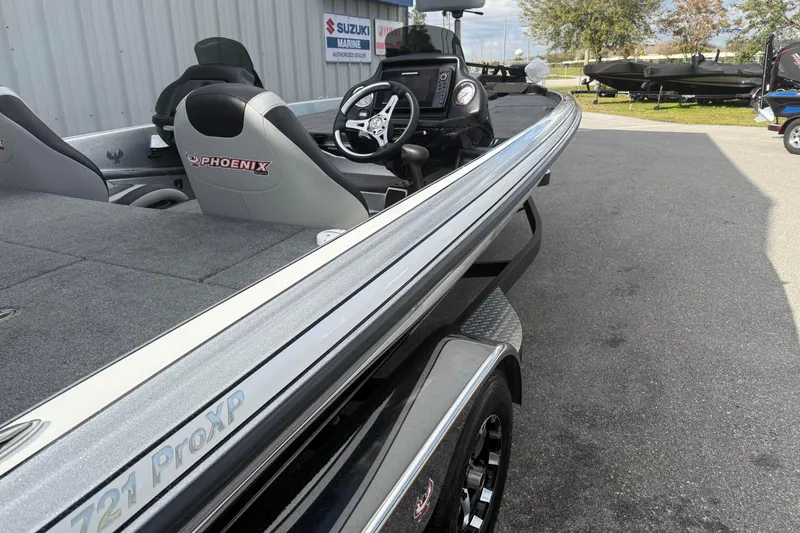 Slide: The Image of 2018 Phoenix 721 ProXP boat with sleek design, parked near Suzuki Marine dealership. - 4