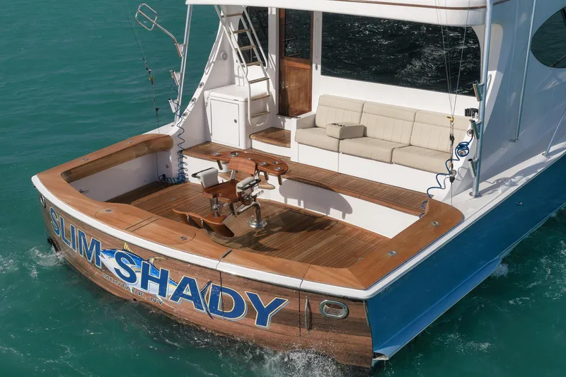 Slide: The Image of 2015 Hatteras GT70 yacht with wooden deck, fishing chair, and cushioned seating. - 12