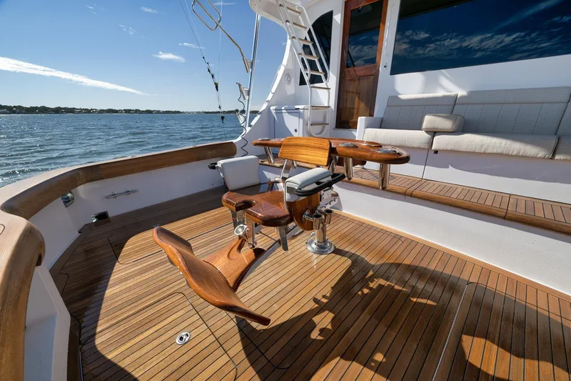 Slide: The Image of 2015 Hatteras GT70 yacht with wooden deck, fishing chair, and cushioned seating. - 13