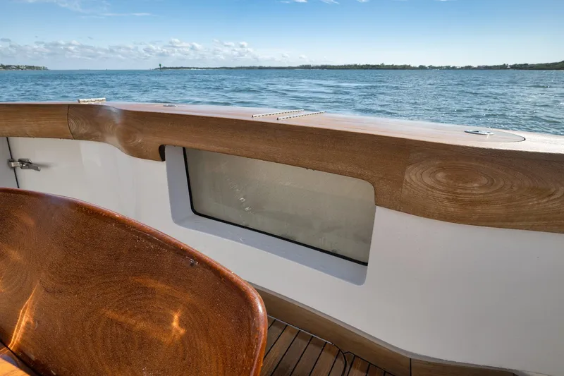 Slide: The Image of Luxurious 2015 Hatteras GT70 yacht deck with wooden finish, overlooking serene waters. - 15