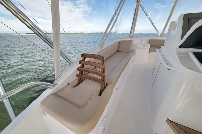 Slide: The Image of 2015 Hatteras GT70 yacht interior with open storage compartment, beige seating, and ocean view. - 69