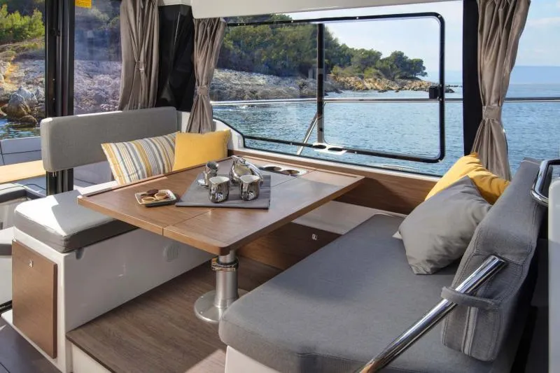 Slide: The Image of 2019 Jeanneau NC 1095 interior with blue cushioned seating and marina view. - 18