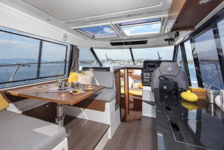 Slide: The Image of Manufacturer Provided Image: 2019 Jeanneau NC 1095 motorboat cruising on clear blue water near a forested shoreline. - 8